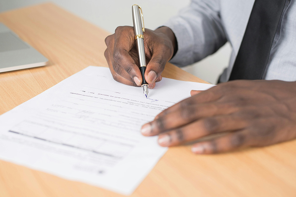 Blank man signing a lease agreement, showing just hands and a pen.