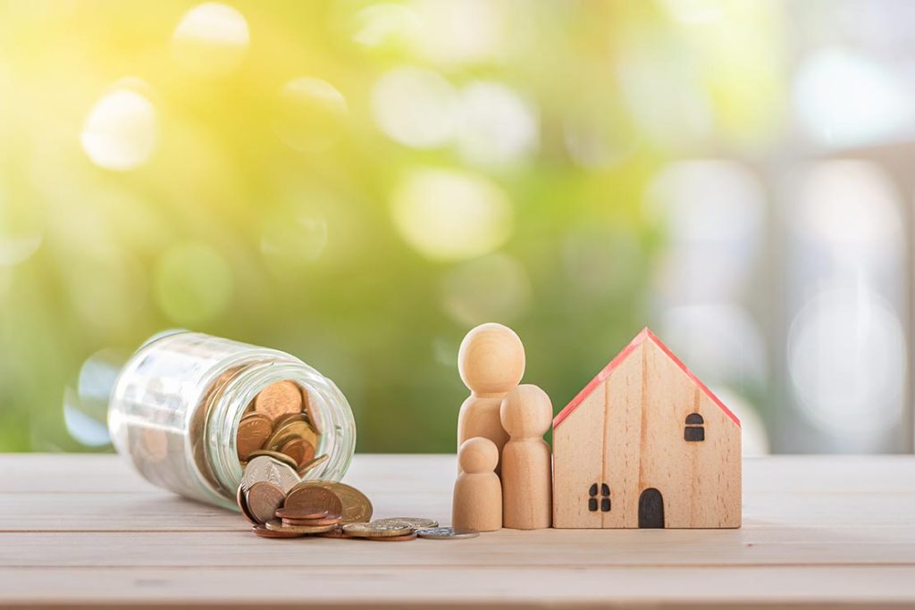 toy wooden house with coins in a jar