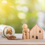 toy wooden house with coins in a jar