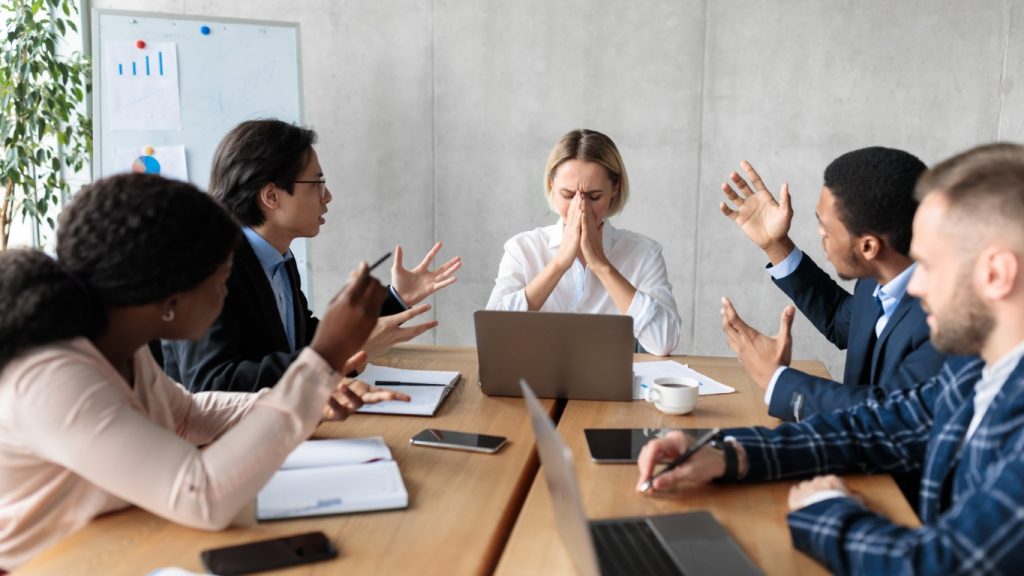 People at a table arguing with female leader at the head of the table