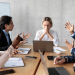 People at a table arguing with female leader at the head of the table