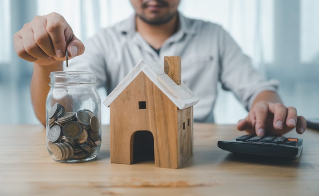 tiny wooden house with a man holding keys.