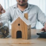 tiny wooden house with a man holding keys.