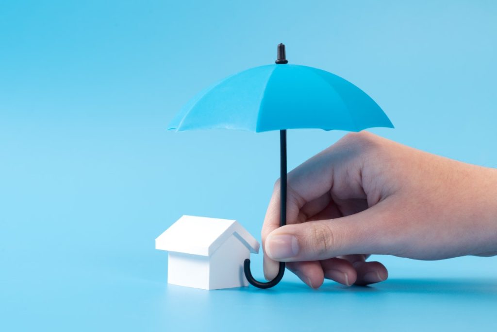 umbrella over a small house indicating insurance.