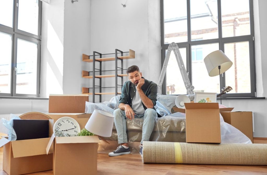 sad man sitting in an apartment with moving boxes