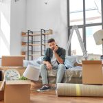 sad man sitting in an apartment with moving boxes