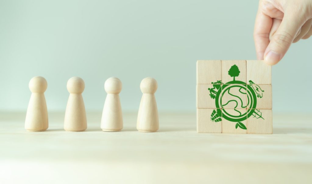 four wooden pawns next to green graphic of a environmental scene